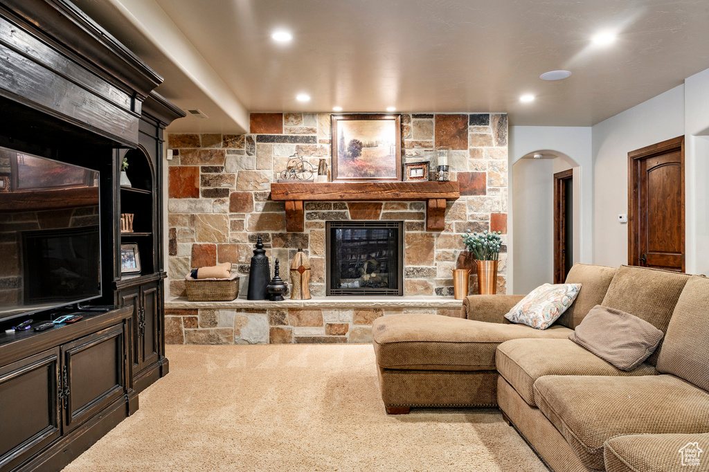 Carpeted living area with recessed lighting, arched walkways, and a fireplace