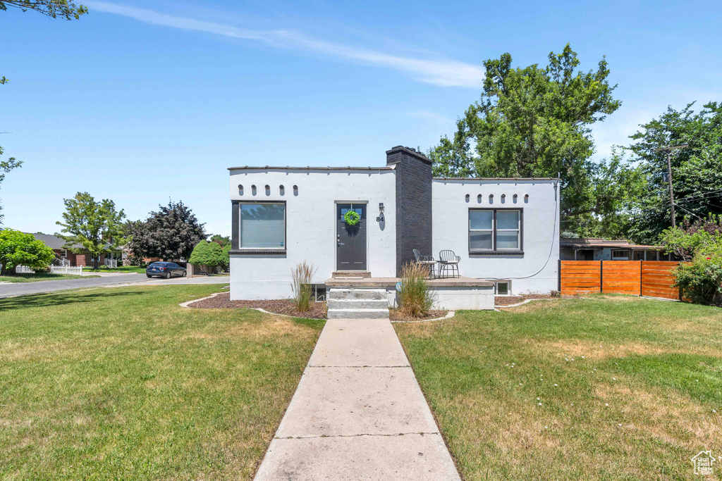Mediterranean / spanish-style house featuring fence, stucco siding, a chimney, and a front yard
