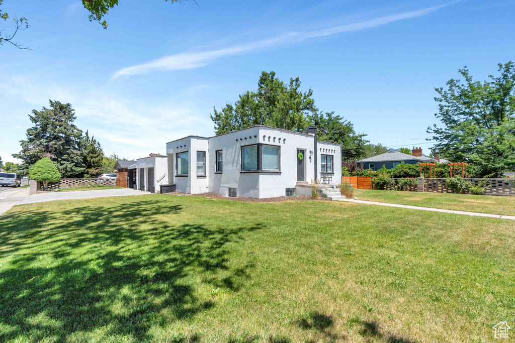 View of front of property with fence, stucco siding, and a front yard
