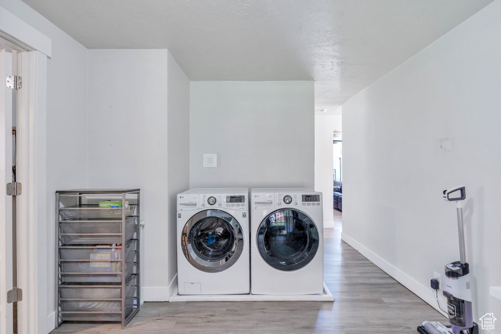Laundry area with independent washer and dryer, laundry area, baseboards, and wood finished floors