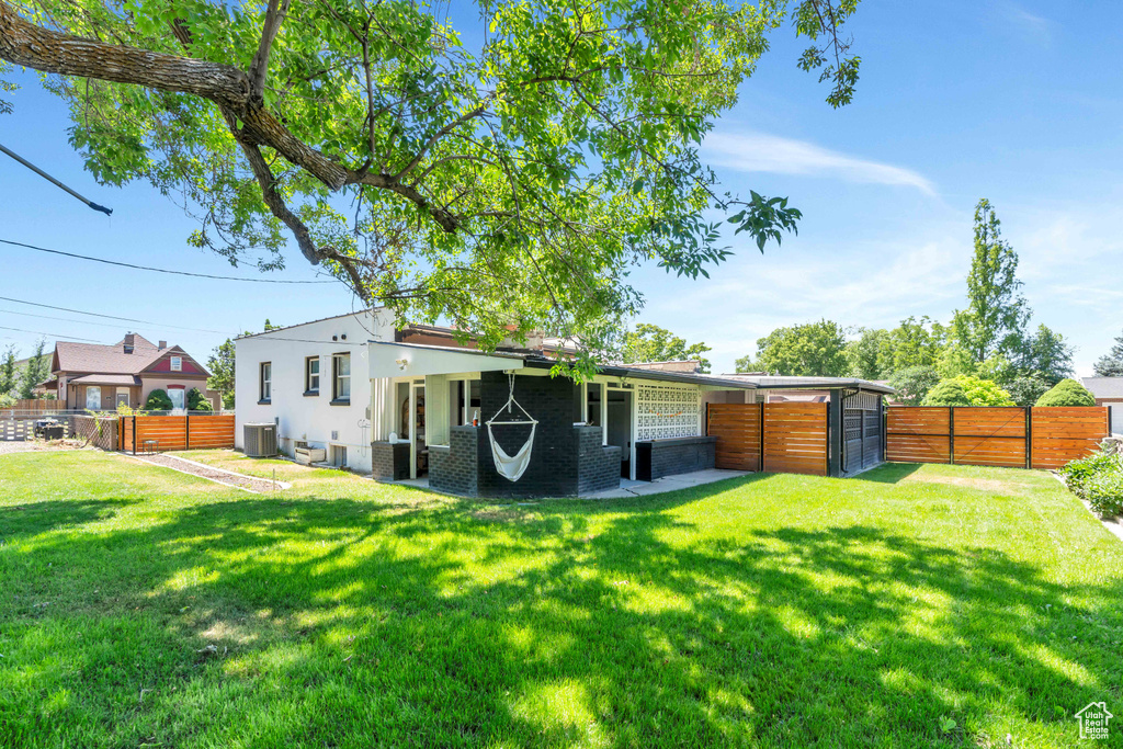 Back of house with a lawn, a fenced backyard, and central AC