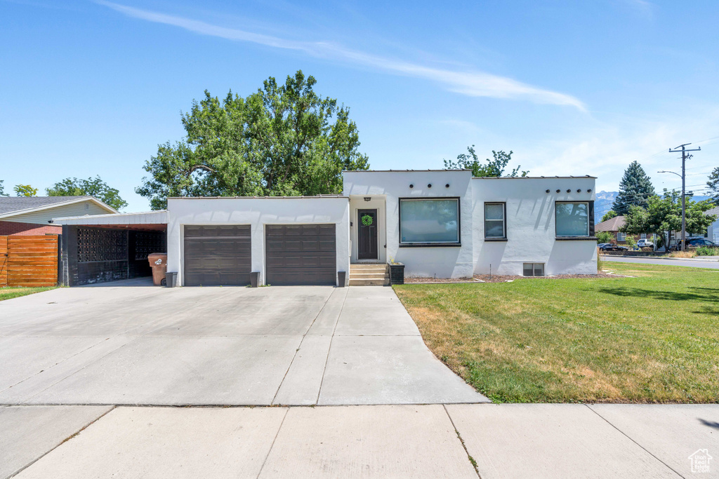 Modern home with a garage, stucco siding, driveway, and a front lawn