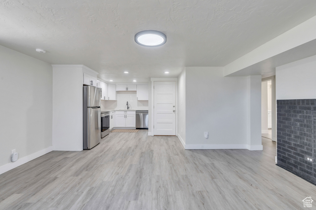 Unfurnished living room with baseboards, recessed lighting, and light wood-style flooring