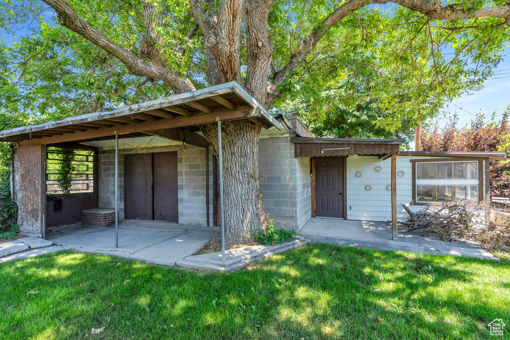 Exterior space featuring concrete block siding, a patio area, and a front yard