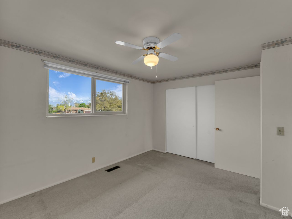 Empty room featuring visible vents, baseboards, ceiling fan, and light colored carpet