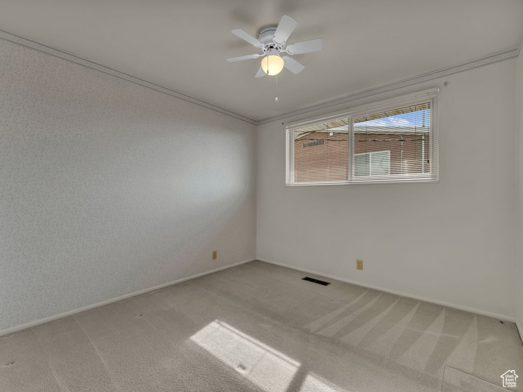 Empty room with ceiling fan, visible vents, light carpet, and baseboards