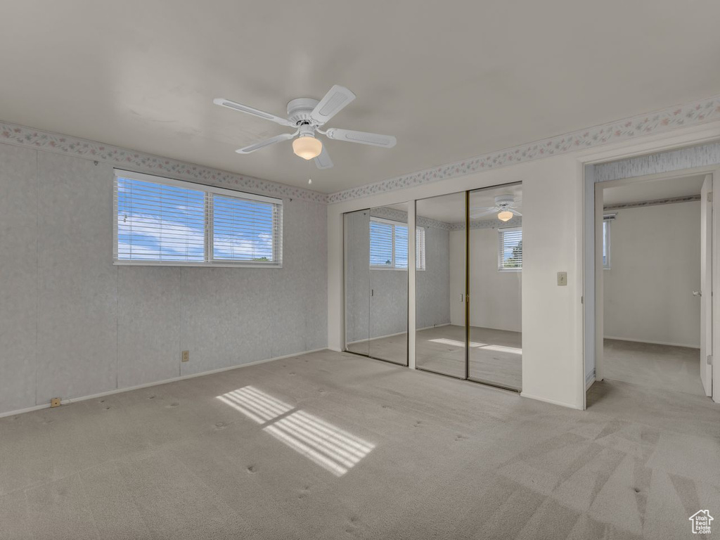 Unfurnished bedroom featuring carpet floors, ceiling fan, and wallpapered walls