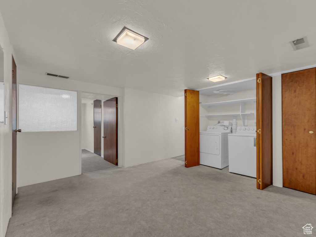 Carpeted spare room with visible vents and independent washer and dryer