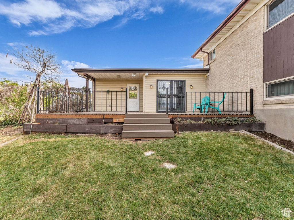 Rear view of house with a lawn and a deck