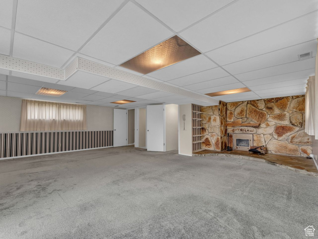 Below grade area featuring visible vents, carpet flooring, a paneled ceiling, and a fireplace