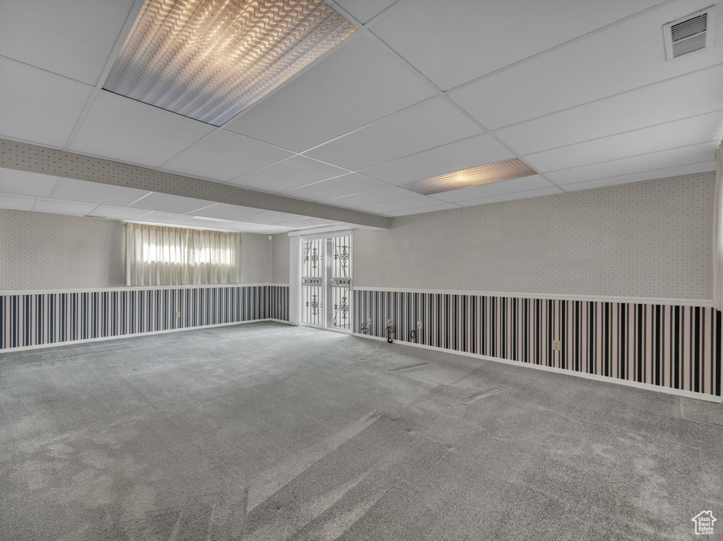 Basement featuring carpet floors, visible vents, and a paneled ceiling