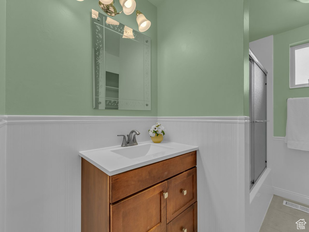 Bathroom with shower / bath combination with glass door, vanity, tile patterned floors, a wainscoted wall, and visible vents