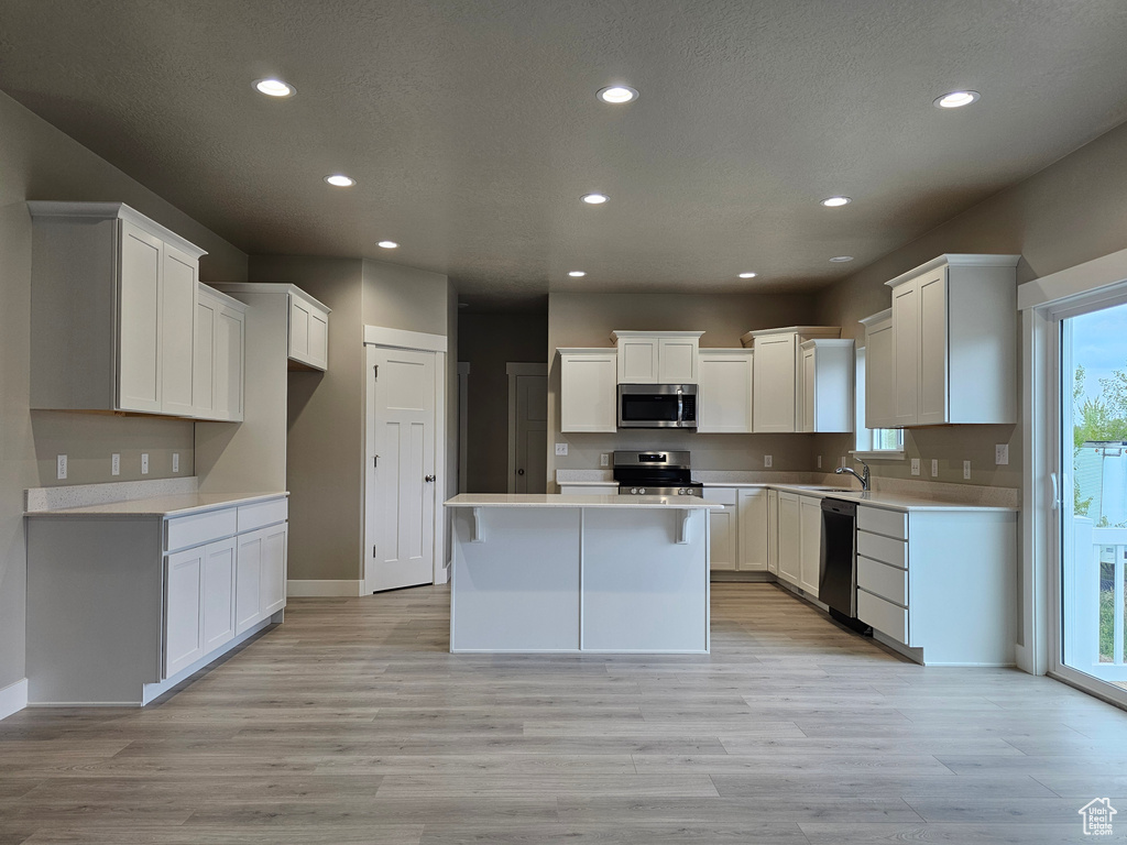 Kitchen featuring recessed lighting, light wood-style floors, appliances with stainless steel finishes, and a kitchen island