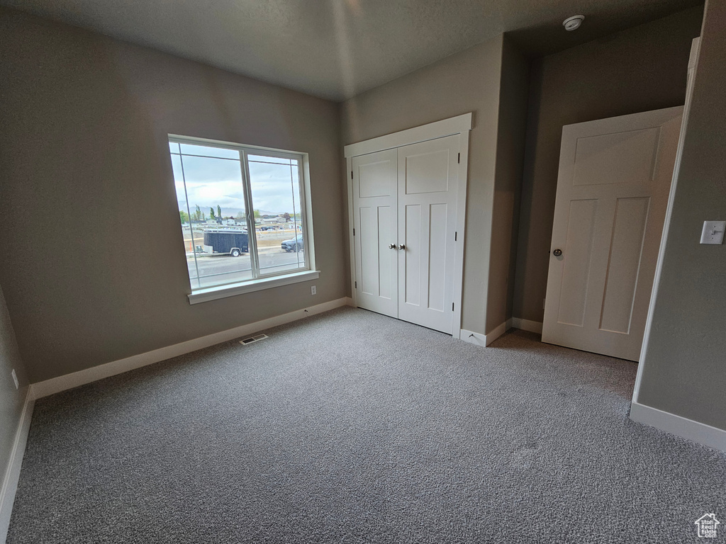 Unfurnished bedroom with visible vents, carpet, and baseboards