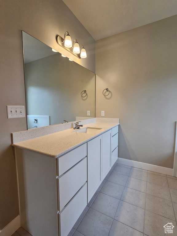 Bathroom with baseboards, tile patterned floors, and vanity