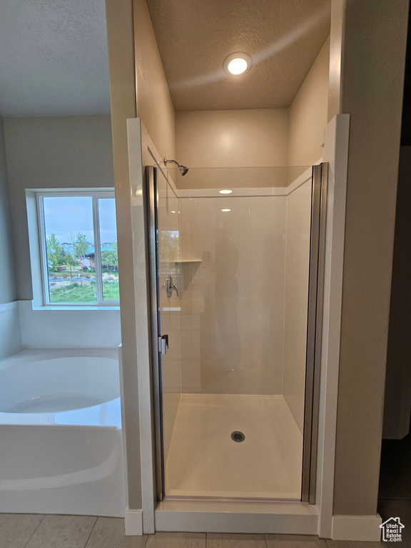 Bathroom featuring a garden tub, tile patterned floors, a textured ceiling, and a stall shower
