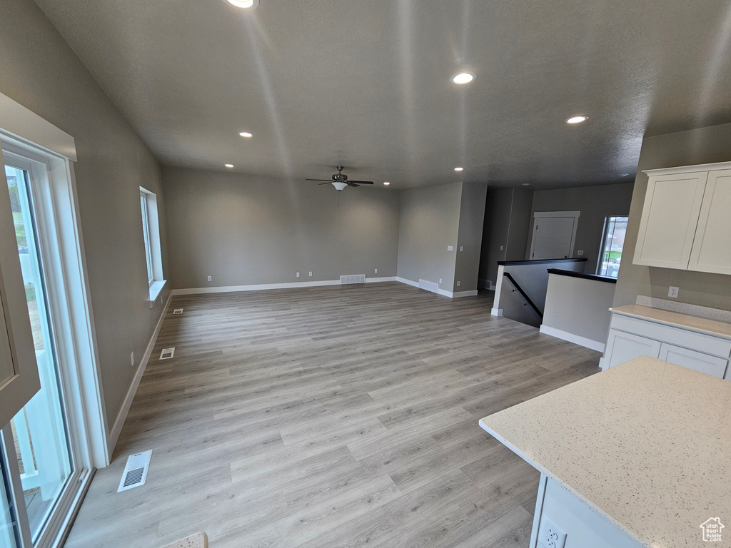 Unfurnished living room with baseboards, ceiling fan, light wood-style flooring, and visible vents