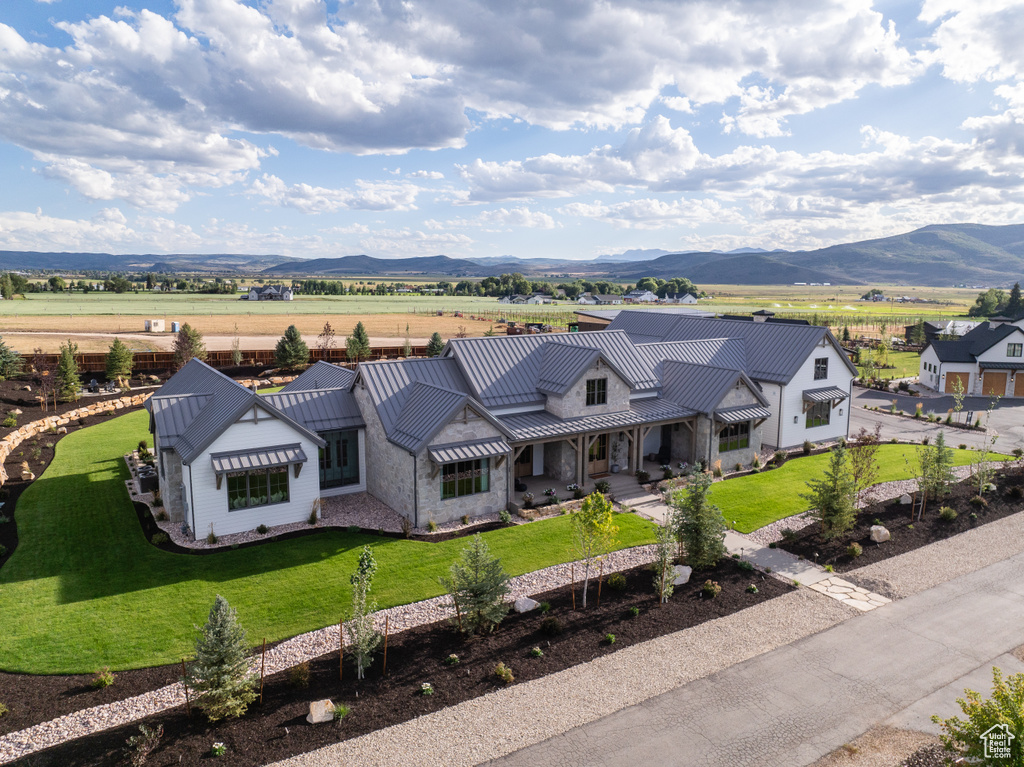 View of front of house with a front lawn, a mountain view, metal roof, and a standing seam roof