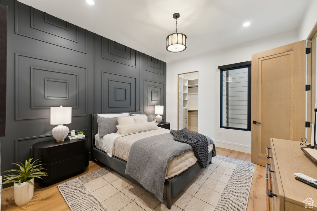 Bedroom featuring a closet, baseboards, a walk in closet, recessed lighting, and light wood-style flooring