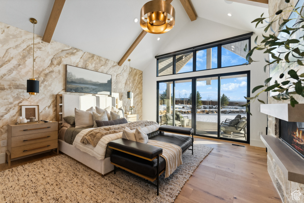 Bedroom with wood finished floors, high vaulted ceiling, beamed ceiling, a glass covered fireplace, and access to outside