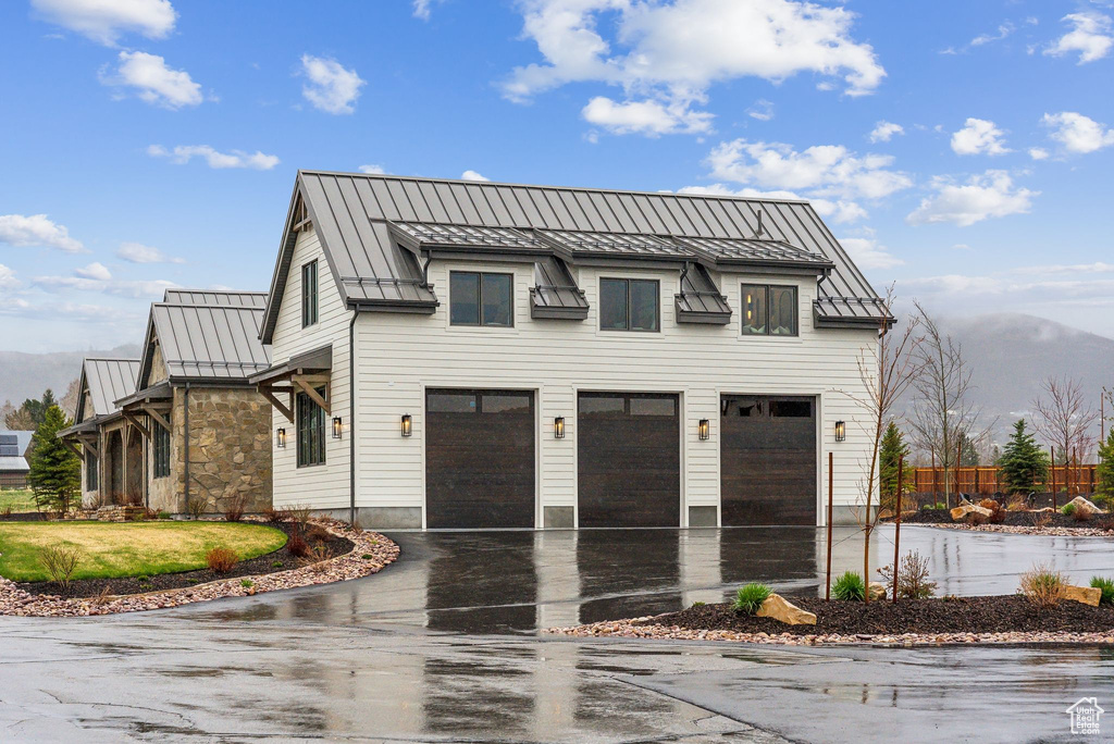 Exterior space with a garage, aphalt driveway, fence, a standing seam roof, and metal roof