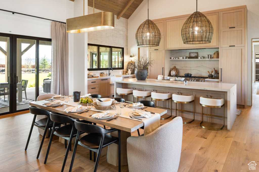 Dining room with high vaulted ceiling, a wealth of natural light, and light wood-style floors