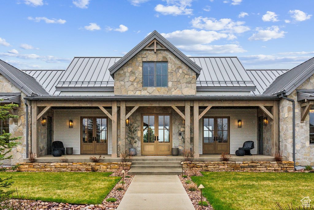 Property entrance with a standing seam roof, french doors, metal roof, and stone siding