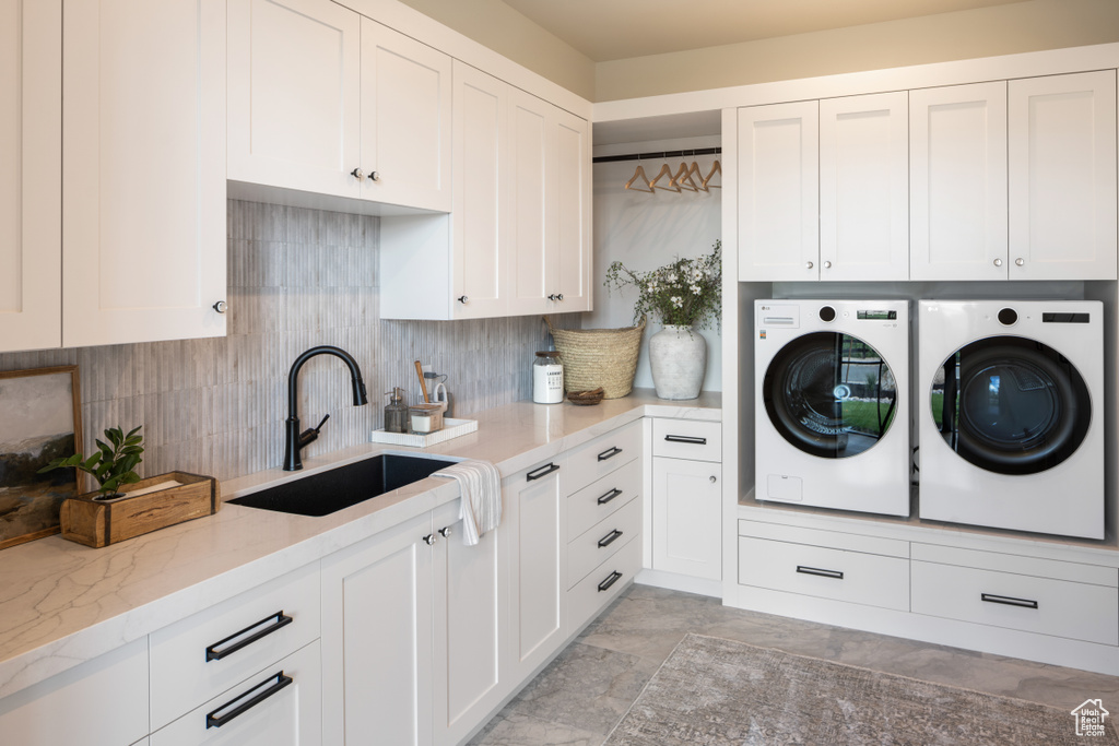 Washroom with cabinet space, a sink, and washer and dryer