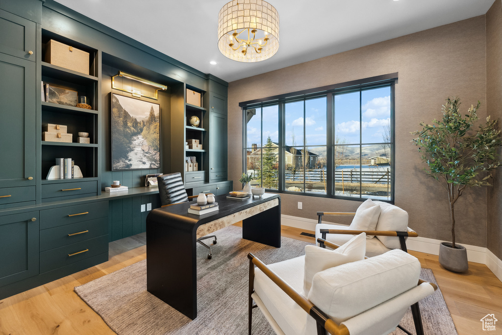 Office area with baseboards, light wood-style flooring, and a chandelier