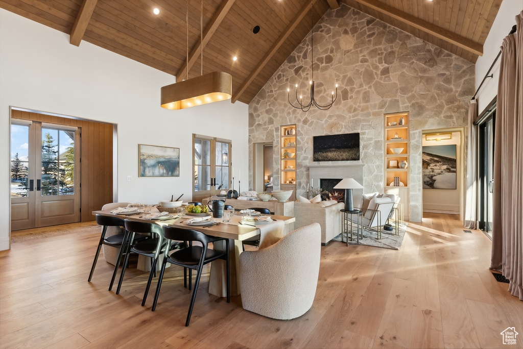 Dining room with beam ceiling, high vaulted ceiling, french doors, light wood-style flooring, and wood ceiling
