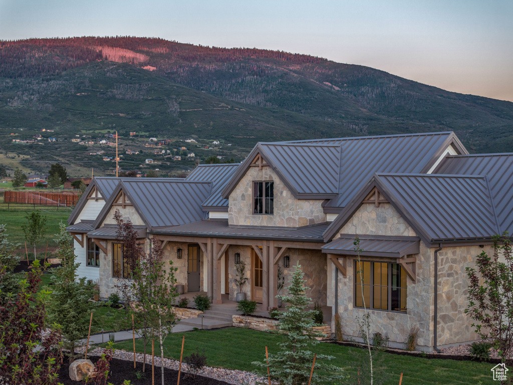 View of front of home with a standing seam roof, a mountain view, metal roof, and stone siding