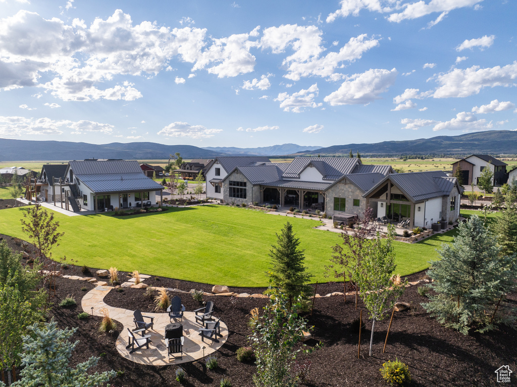 Rear view of property with a lawn, a fire pit, a mountain view, and a patio area