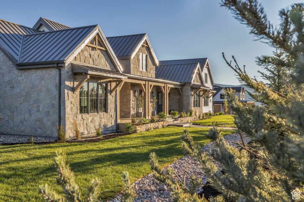 Back of house with a standing seam roof, a lawn, metal roof, and stone siding