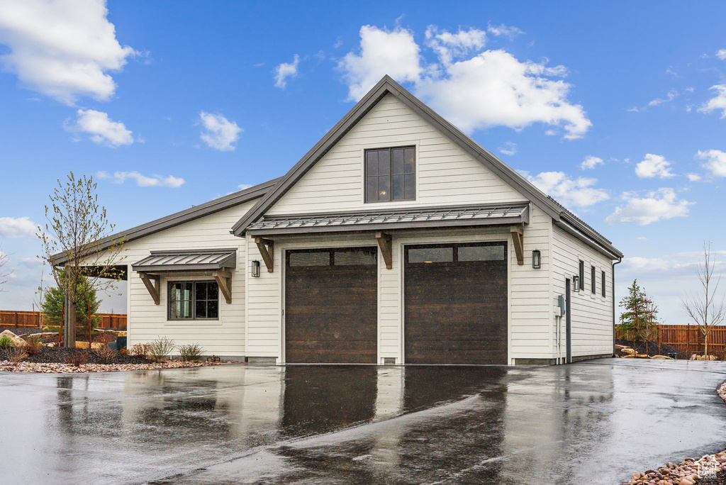 View of front of home featuring fence, a standing seam roof, metal roof, and a garage