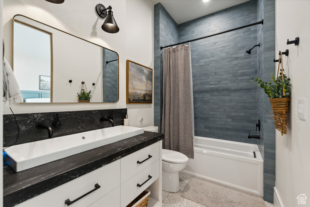 Full bathroom featuring vanity, shower / tub combo with curtain, and toilet