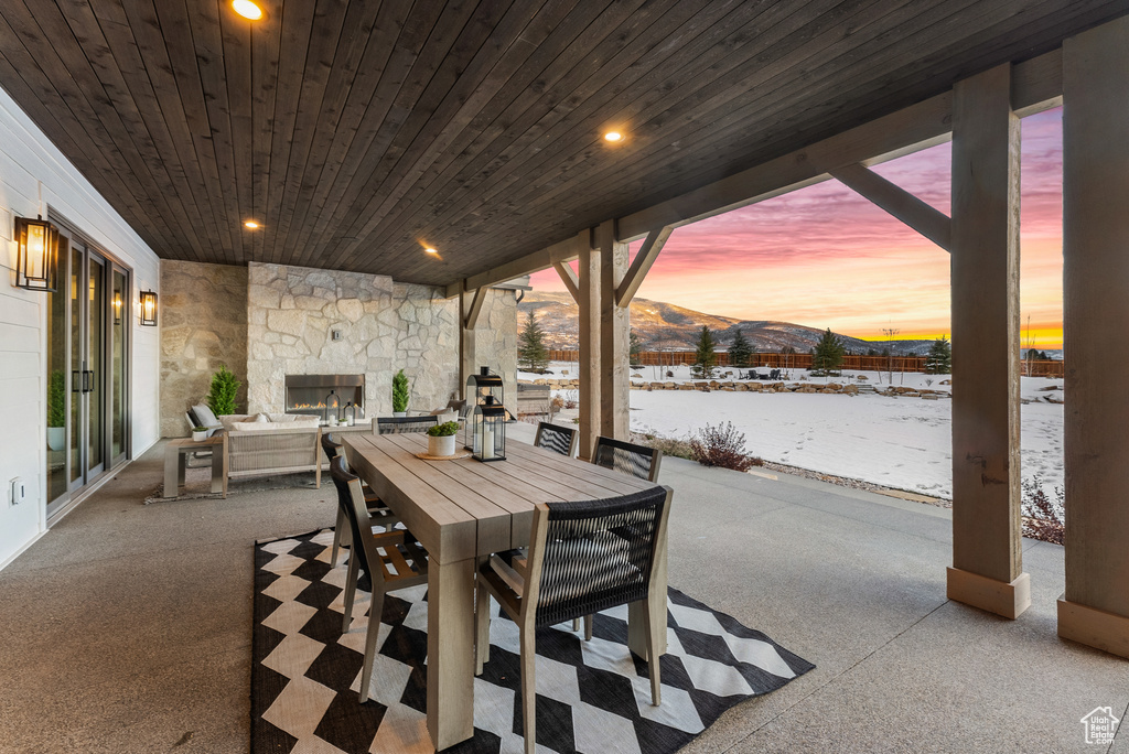 View of patio featuring an outdoor stone fireplace, outdoor dining area, and a mountain view