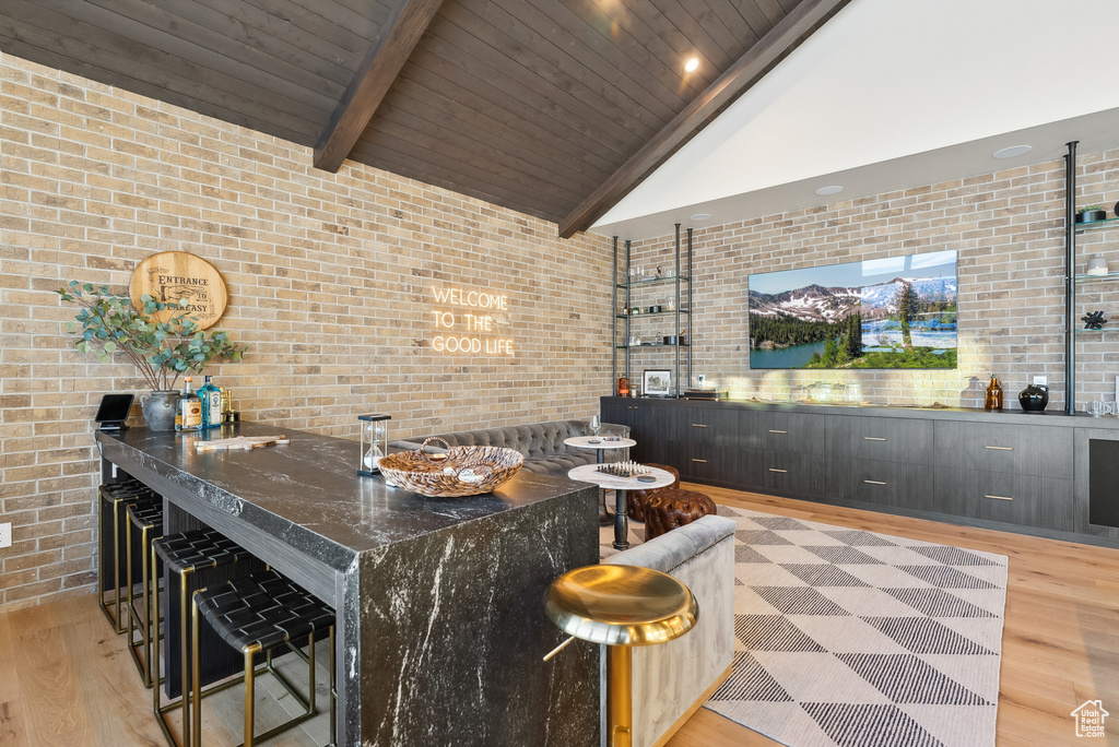 Bar featuring brick wall, light wood-style floors, high vaulted ceiling, wooden ceiling, and wet bar