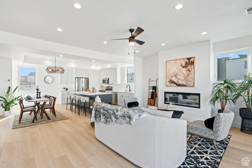 Living room featuring recessed lighting, a ceiling fan, light wood-style flooring, and a healthy amount of sunlight