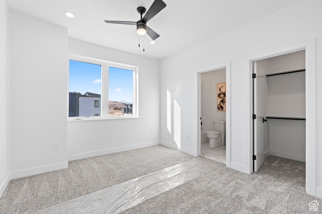 Unfurnished bedroom featuring baseboards, carpet, connected bathroom, and a walk in closet