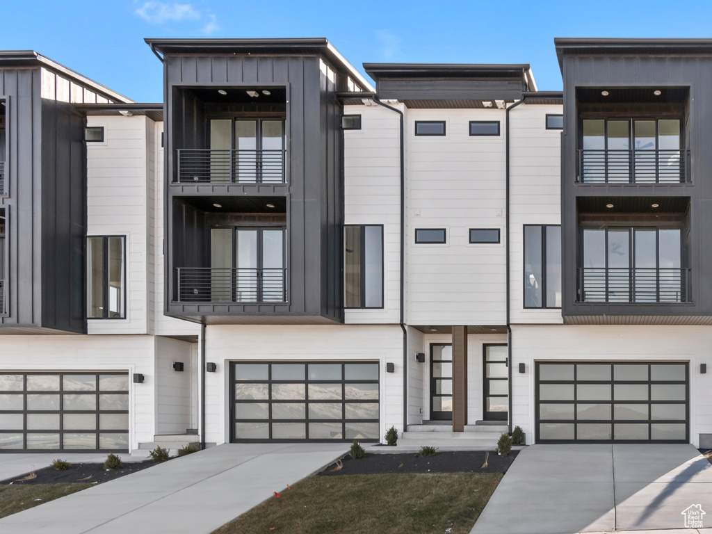 View of front of home featuring concrete driveway, an attached garage, board and batten siding, and a residential view