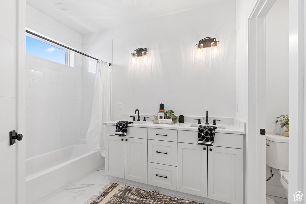Full bathroom featuring double vanity, marble finish floor, shower / bath combination with curtain, toilet, and a sink
