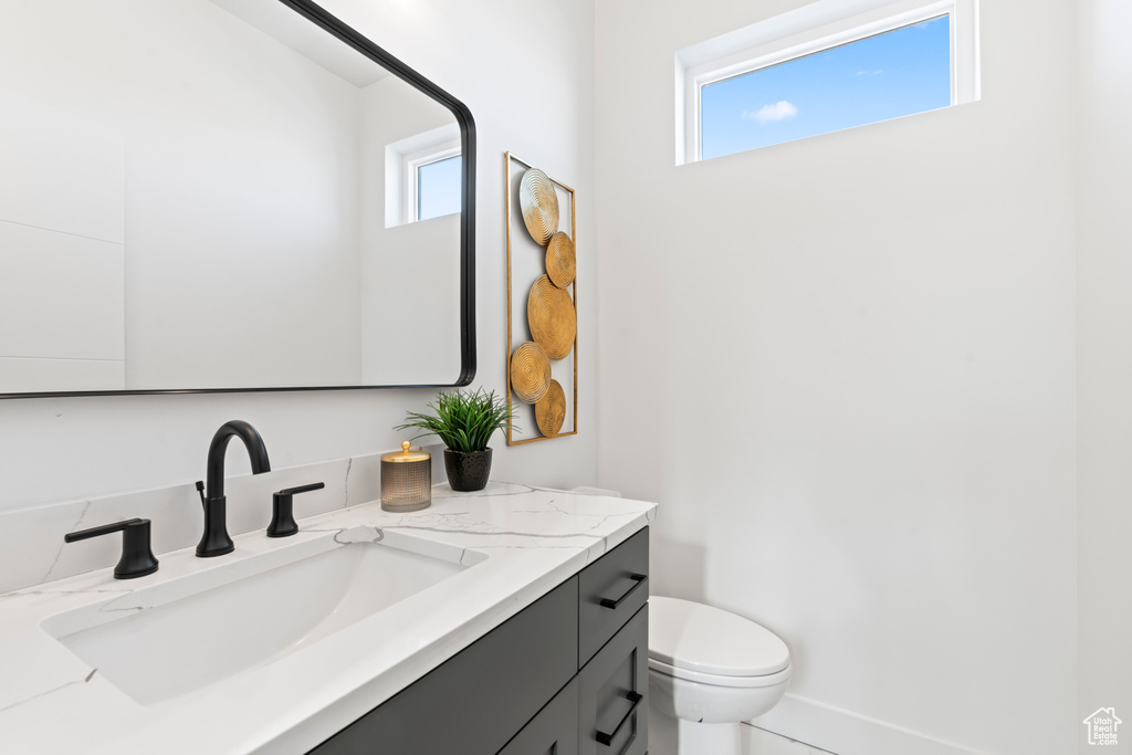 Half bath with toilet, plenty of natural light, and vanity