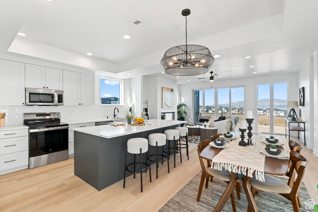 Kitchen with a breakfast bar area, stainless steel appliances, recessed lighting, and light wood finished floors