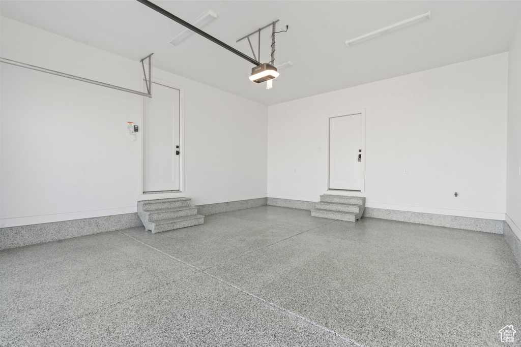 Garage featuring baseboards and a garage door opener