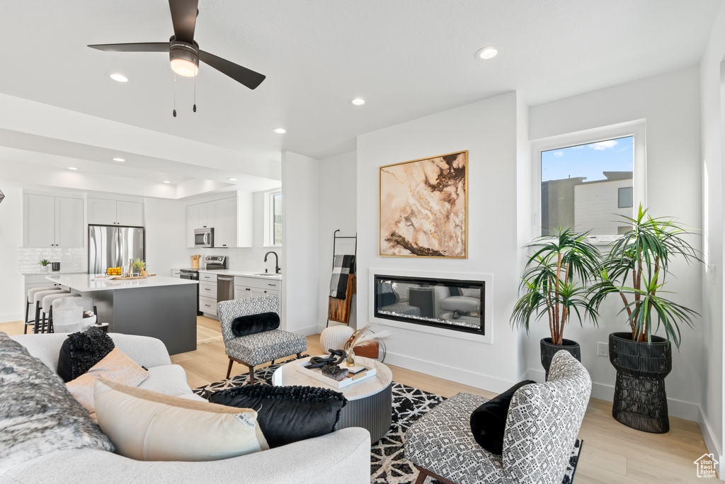 Living room featuring recessed lighting, ceiling fan, baseboards, and light wood-style floors