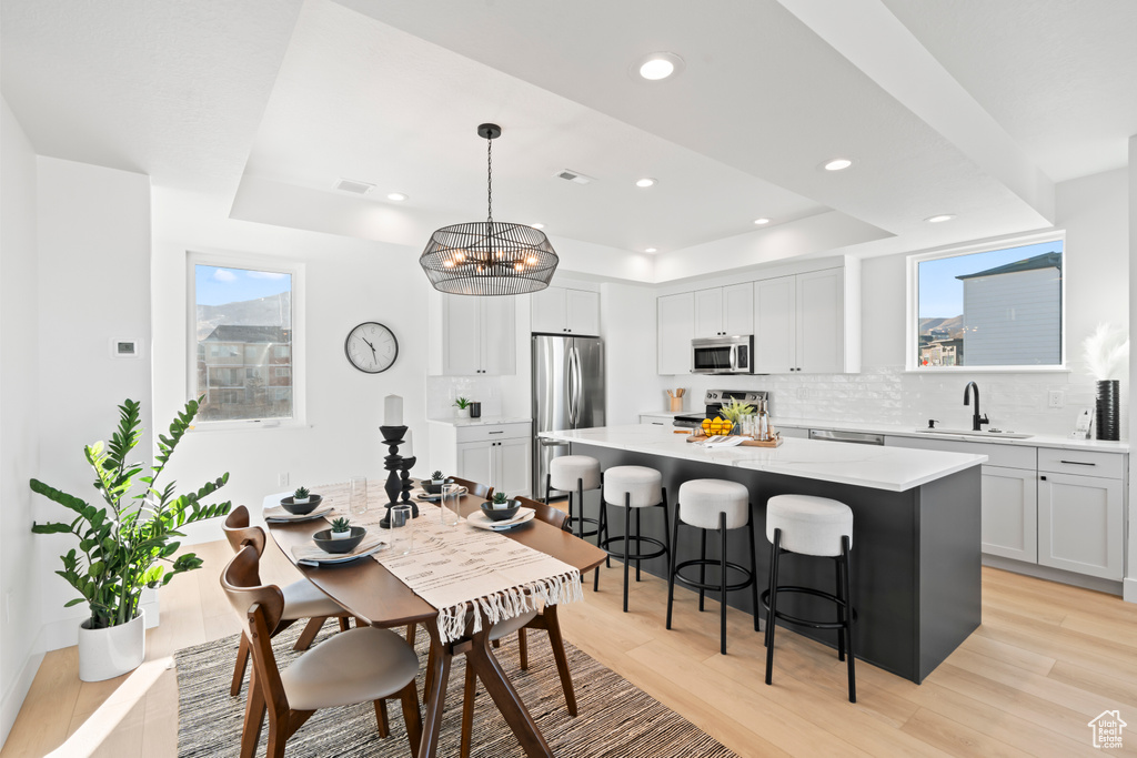 Kitchen featuring a sink, a raised ceiling, a breakfast bar area, stainless steel appliances, and backsplash