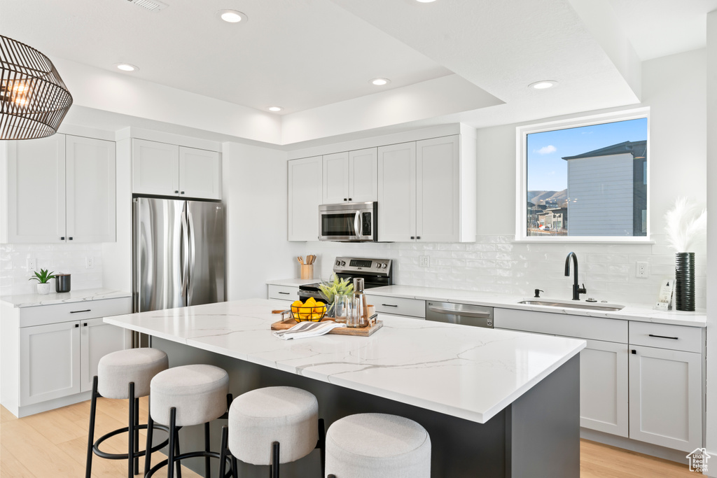 Kitchen featuring appliances with stainless steel finishes, a breakfast bar, a sink, and a center island