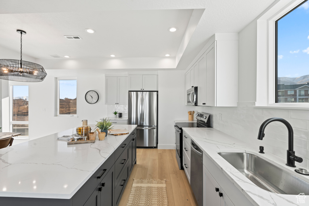 Kitchen with tasteful backsplash, light wood-type flooring, a sink, stainless steel appliances, and recessed lighting