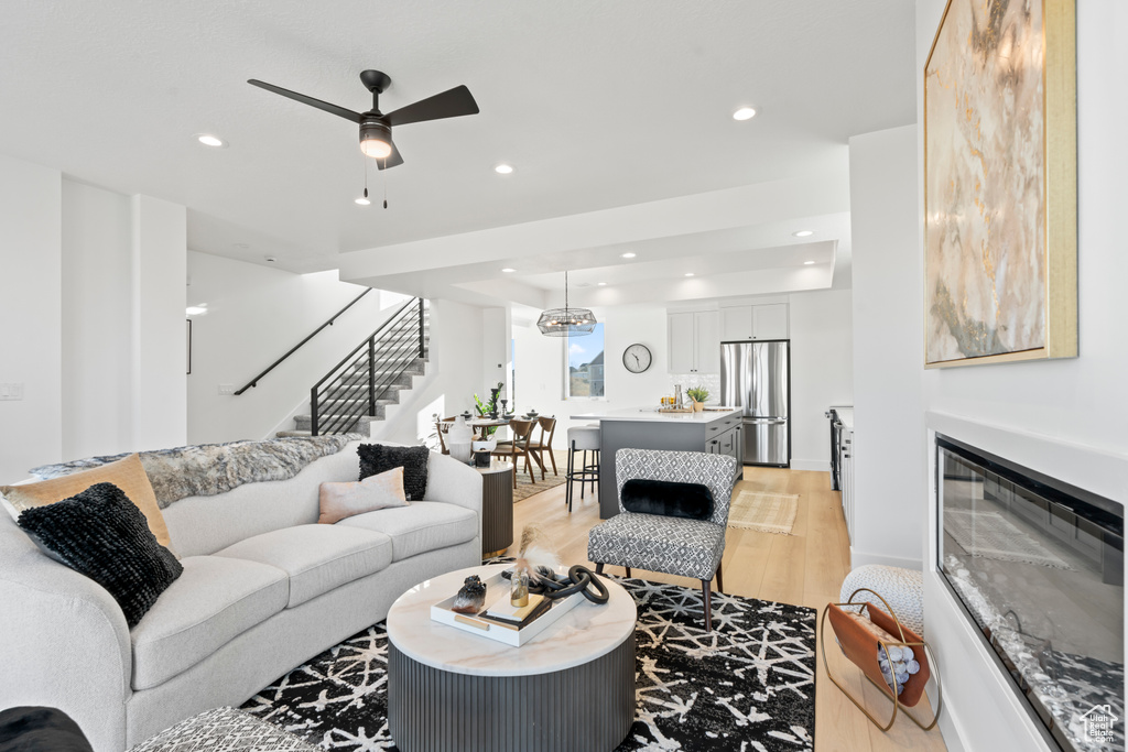 Living area with recessed lighting, stairs, ceiling fan, and light wood-style floors