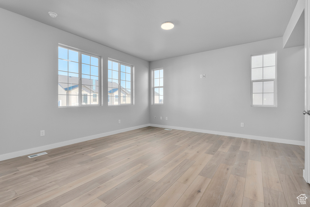 Spare room featuring light wood-style floors, baseboards, and visible vents